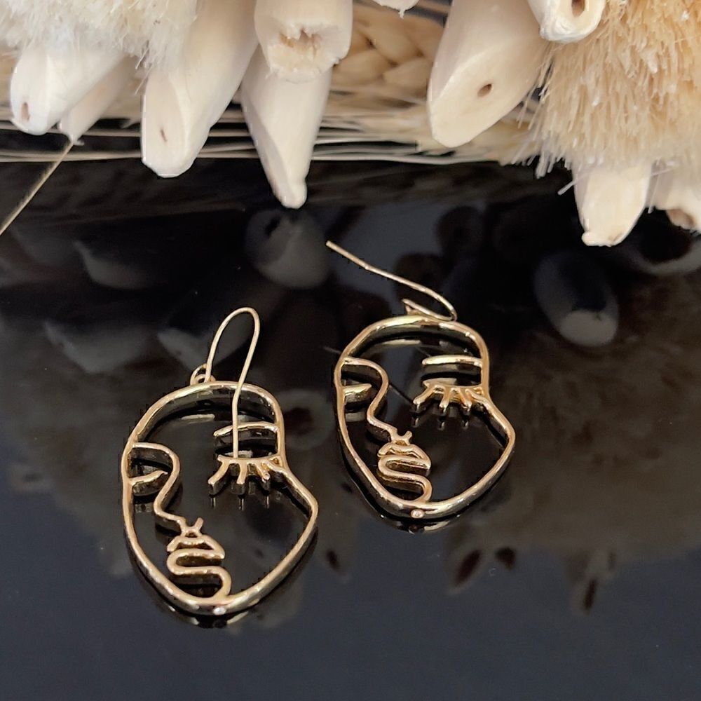 Gold tone earrings with faces on them